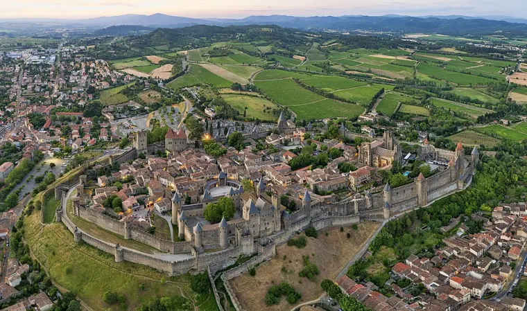 Vue aérienne de la Cité de Carcassonne : la double enceinte, ses tours et les toits de la cité.